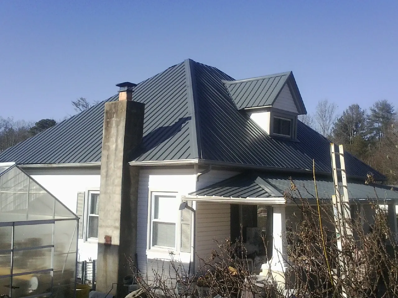 Dark blue standing seam metal roof on a white farmhouse with dormer — Slate & Tile Roof Repair by Roofing Brothers in Cantonment