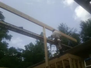 Carpenter setting a ridge beam over a new addition frame — Ice Dam Removal by Roofing Brothers in Cantonment