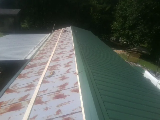 Old rusted panels beside newly installed green metal roofing — Wind Damage Roof Repair by Roofing Brothers in Cantonment
