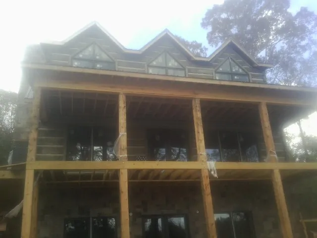 Dormers and porch framing on a large log home under construction — Roof Coating work by our crew in Cantonment