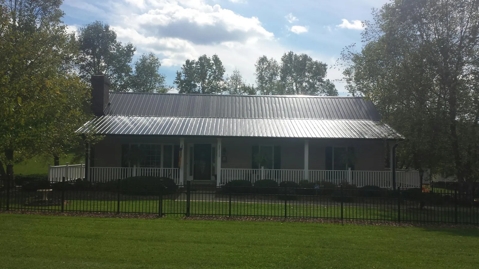 Gray metal roof on a brick ranch with a full width front porch — Gutter Guard Installation work by our crew in Cantonment