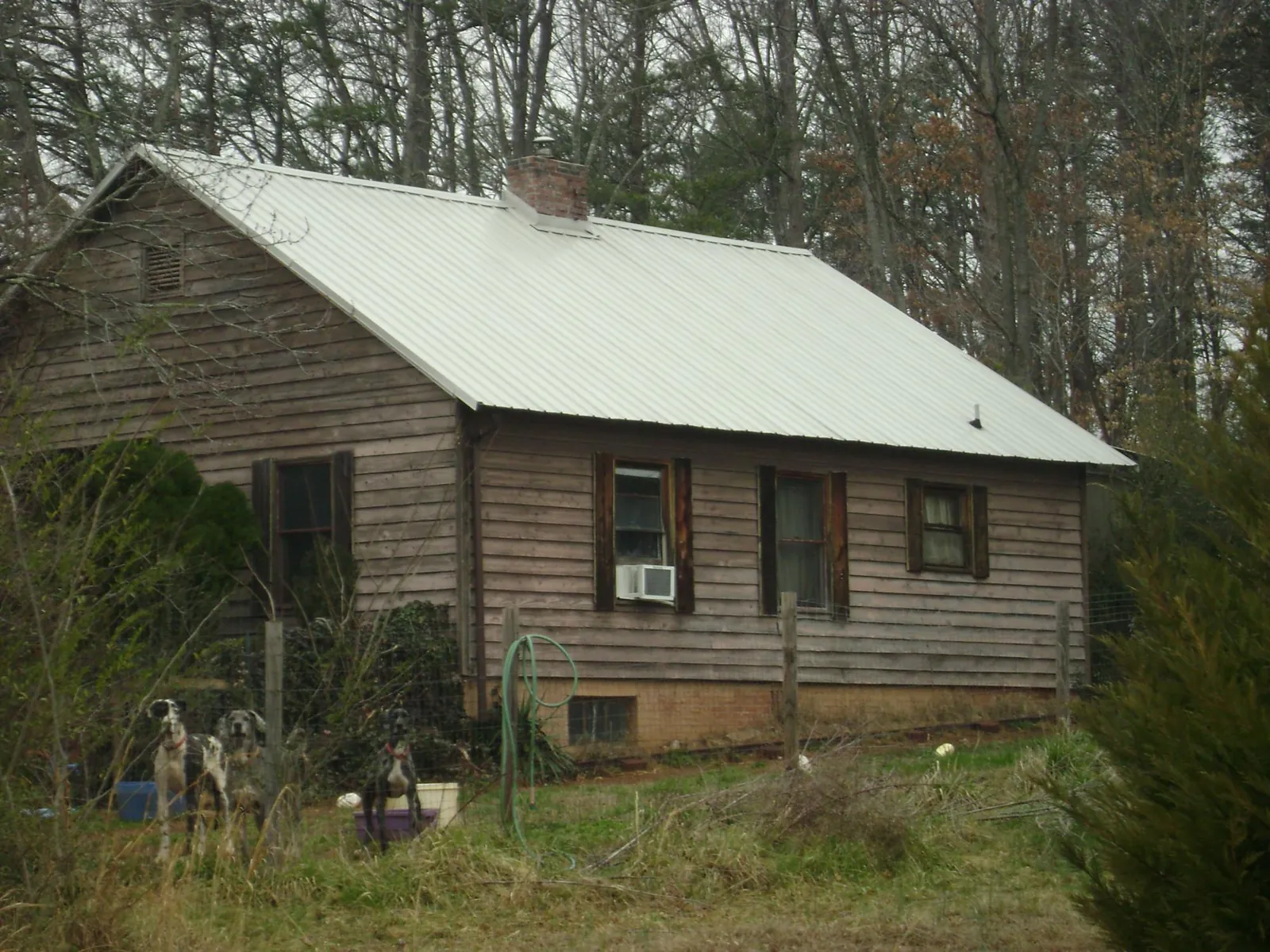White metal roof on an old wood sided farmhouse, from a Metal Roof Installation job in Cantonment