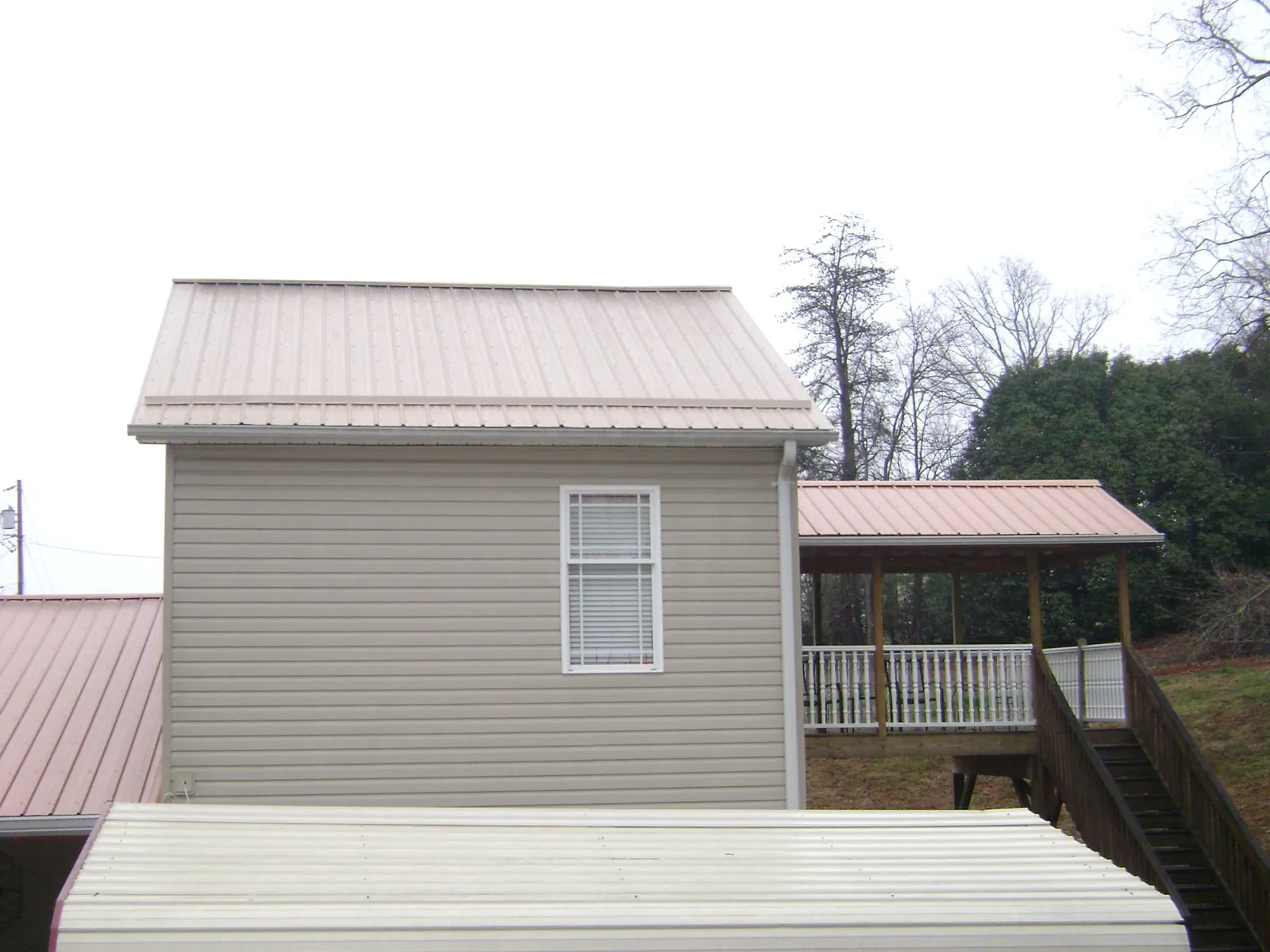 Tan metal roofs on a two story addition and attached porch, from a Roof Replacement job in Cantonment