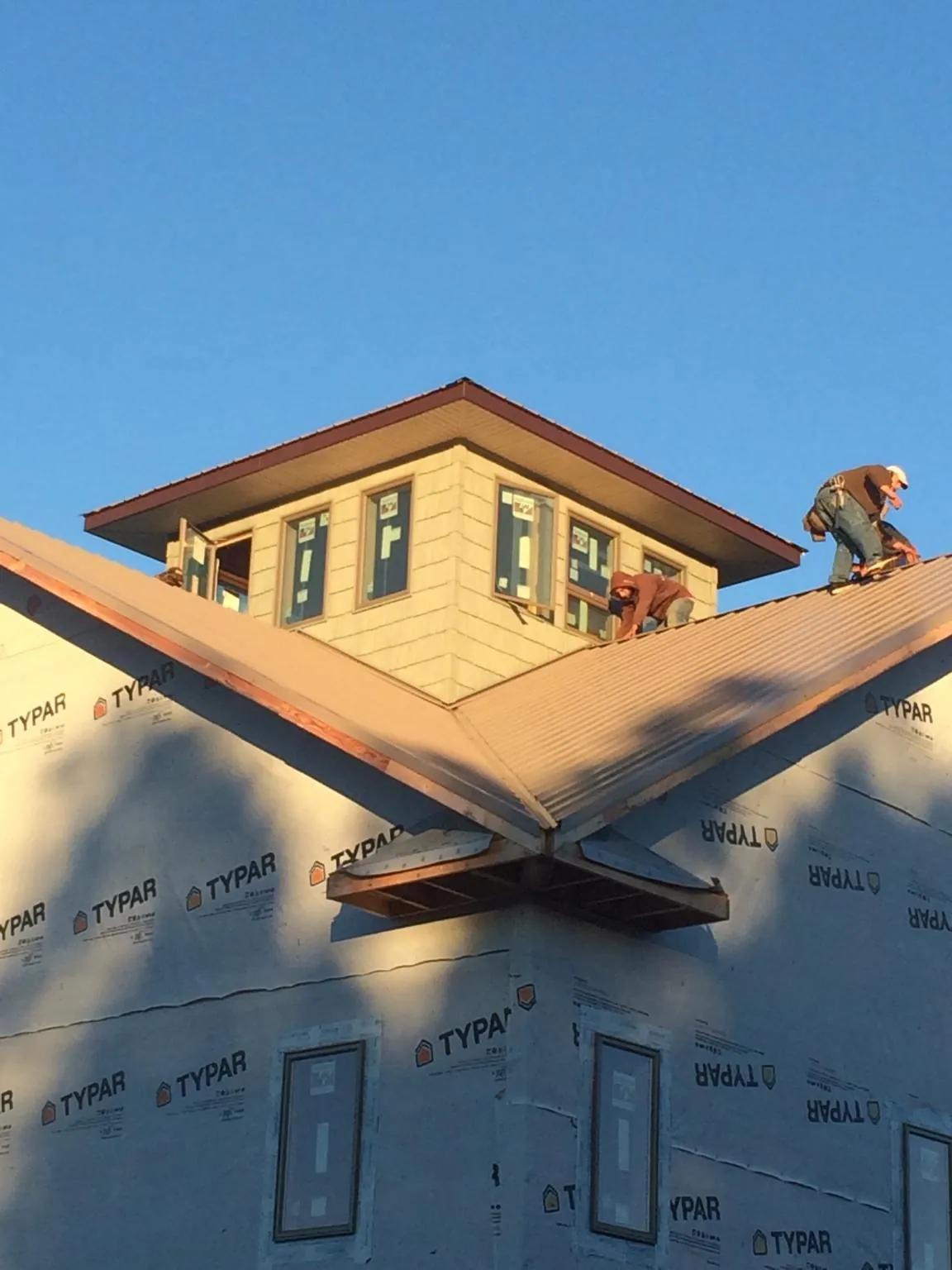 Roofers working around a rooftop cupola on a new metal roof at sunset — Roof Waterproofing in Cantonment by Roofing Brothers